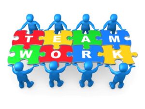 Royalty-free futuristic business clipart picture of blue 3d people working together to hold colorful pieces of a jigsaw puzzle that spells out "Team Work."